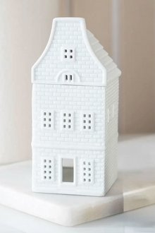 White ceramic house-shaped lantern on a white surface with a neutral background